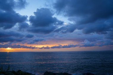 Gökyüzü bulutlu ve güneş batıyor.