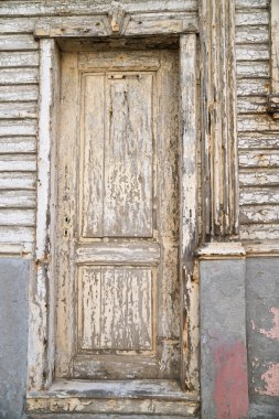 Paslı menteşeli ve soyulmuş boyalı bir kapı. Kapı açık ve çerçeve ahşaptan yapılmış.