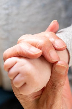 Bir bebeğin eli bir ebeveyn tarafından tutuluyor. Aile sevgisi ve koruma kavramı.