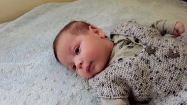 Küçük bir bebeğin portresi. Küçük bebek yatakta mutlu yatıyor.