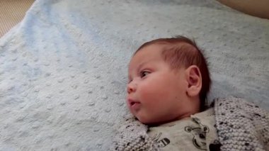 Küçük bir bebeğin portresi. Küçük bebek yatakta mutlu yatıyor.