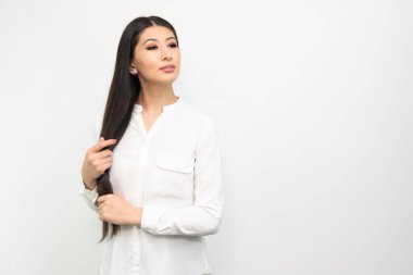 Genç ve güzel siyah uzun saçlı Asyalı kadın beyaz arka planda güven içinde poz veriyor..