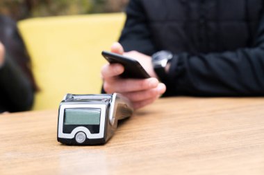 man making contactless payment with smartphone at cafe clipart