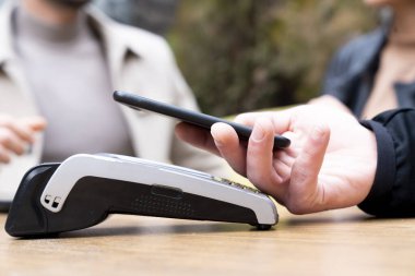 Cafe 'de akıllı telefondan ödeme yapan bir adam.