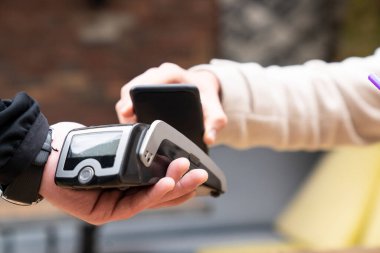 man making contactless payment with smartphone at cafe clipart