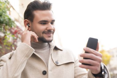 Bir işadamı açık havada mutlu bir gülümseme ile cep telefonuyla konuşan bir telefon görüşmesi yapar ve fotokopi çektirir.