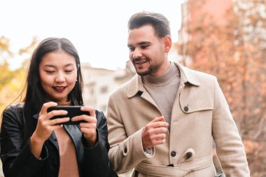 Genç bir çift şehir caddesinde akıllı telefon kullanıyor.