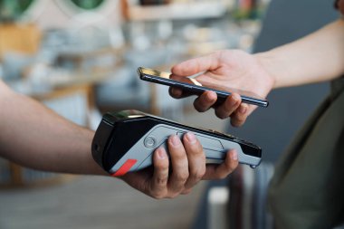 Birisi kredi kartı ve telefonuyla bir şey ödüyor.