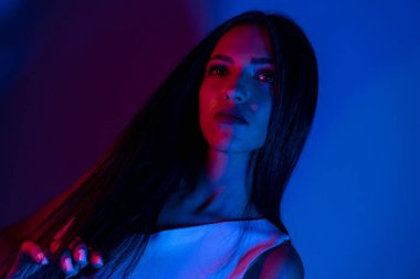 Renkli parlak neon ışıklarıyla stüdyoda poz veren yüksek model kadın. Parlak makyajlı güzel bir kadının portresi. Sanat tasarımı canlı biçimi