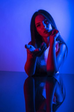 Renkli parlak neon ışıklarıyla stüdyoda poz veren yüksek model kadın. Parlak makyajlı güzel bir kadının portresi. Sanat tasarımı canlı biçimi