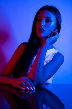 Renkli parlak neon ışıklarıyla stüdyoda poz veren yüksek model kadın. Parlak makyajlı güzel bir kadının portresi. Sanat tasarımı canlı biçimi