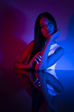Renkli parlak neon ışıklarıyla stüdyoda poz veren yüksek model kadın. Parlak makyajlı güzel bir kadının portresi. Sanat tasarımı canlı biçimi