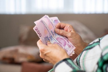 Kırışık ellerin Türk lira banknotlarını tuttuğu yakın plan.