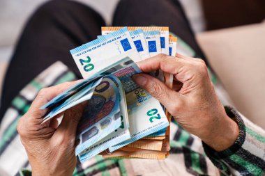 Yaşlı bir emeklinin elinde bir tomar para. Yaşlılıkta finansal güvenlik kavramı.