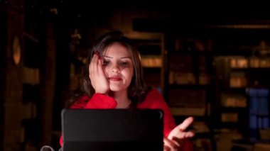 Loş bir odada oturan bir kadın bilgisayar ekranına bakıyor..