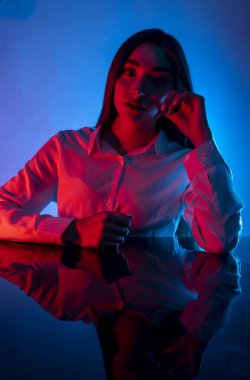 Renkli parlak neon ışıklarıyla stüdyoda poz veren yüksek model kadın. Parlak makyajlı güzel bir kadının portresi. Sanat tasarımı canlı biçimi