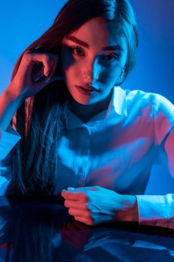 Renkli parlak neon ışıklarıyla stüdyoda poz veren yüksek model kadın. Parlak makyajlı güzel bir kadının portresi. Sanat tasarımı canlı biçimi