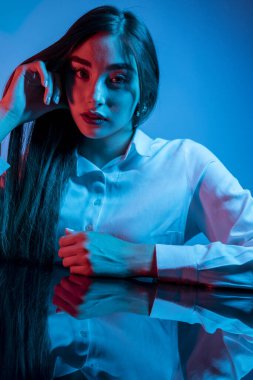 Renkli parlak neon ışıklarıyla stüdyoda poz veren yüksek model kadın. Parlak makyajlı güzel bir kadının portresi. Sanat tasarımı canlı biçimi