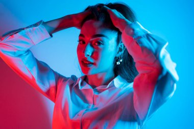 Renkli parlak neon ışıklarıyla stüdyoda poz veren yüksek model kadın. Parlak makyajlı güzel bir kadının portresi. Sanat tasarımı canlı biçimi