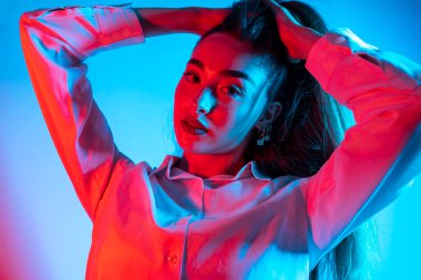 Renkli parlak neon ışıklarıyla stüdyoda poz veren yüksek model kadın. Parlak makyajlı güzel bir kadının portresi. Sanat tasarımı canlı biçimi