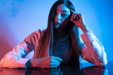 Renkli parlak neon ışıklarıyla stüdyoda poz veren yüksek model kadın. Parlak makyajlı güzel bir kadının portresi. Sanat tasarımı canlı biçimi