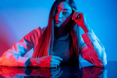 Renkli parlak neon ışıklarıyla stüdyoda poz veren yüksek model kadın. Parlak makyajlı güzel bir kadının portresi. Sanat tasarımı canlı biçimi