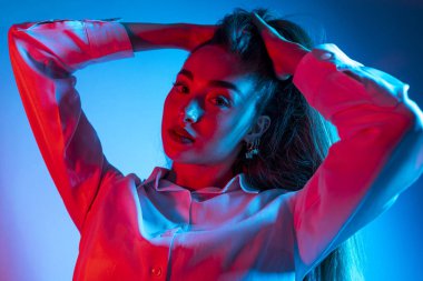 Renkli parlak neon ışıklarıyla stüdyoda poz veren yüksek model kadın. Parlak makyajlı güzel bir kadının portresi. Sanat tasarımı canlı biçimi