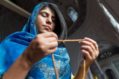 Müslüman kadın camide tespih çekiyor ve dua ediyor.