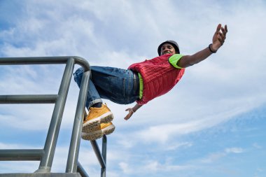 Genç bir adam metal korkuluklarda poz veriyor.