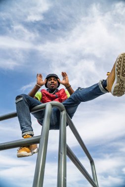 Genç bir adam metal korkuluklarda poz veriyor.