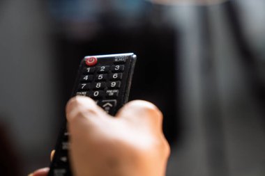 Bir TV kumandası tutan kişi