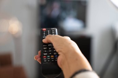 Bir TV kumandası tutan kişi