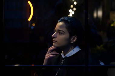 Genç düşünceli kadın gece manzarasına bakıyor.