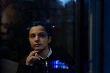 Genç düşünceli kadın gece manzarasına bakıyor.