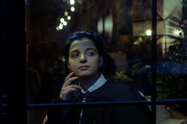 Genç düşünceli kadın gece manzarasına bakıyor.