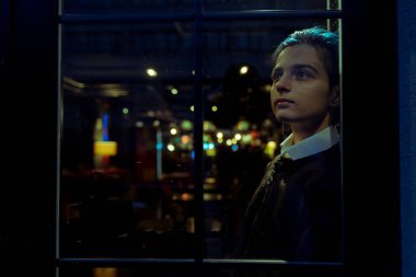 Genç düşünceli kadın gece manzarasına bakıyor.