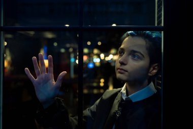 Genç düşünceli kadın gece manzarasına bakıyor.