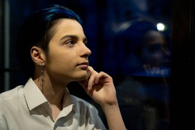 Genç düşünceli kadın gece manzarasına bakıyor.