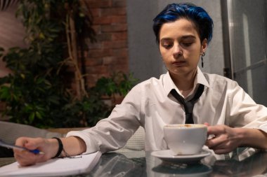 Genç bir kadın akşam kahvesinde okuyor.