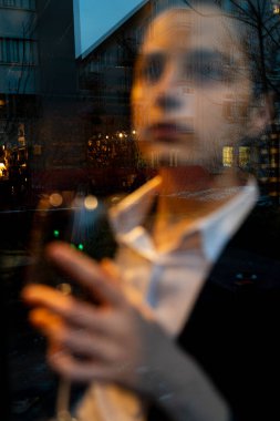 Pencerenin önünde şarap kadehi tutan genç bir kadın.