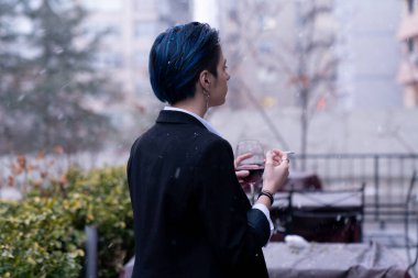 Dışarıda kar yağarken şarap kadehli genç bir kadın.