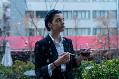 Dışarıda kar yağarken şarap kadehli genç bir kadın.