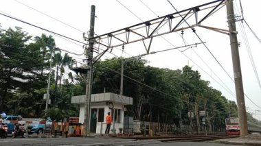 Jakarta, Endonezya - 1 Mayıs 2023: Kavşağı geçen bir KRL banliyö hattı, Güneydoğu Asya 'nın Jakarta kentinde bir elektrikli toplu taşıma trenidir. Jakarta 'daki Endonezya Hükümeti tarafından desteklenen çevre dostu bir toplu taşıma hizmeti..