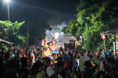 Hint bayramındaki Diwali festivali sırasında bir kadın ve tanrıların heykelini taşıyan bir kadın tarafından kafaya geçirilmiş bir şiş heykeli..