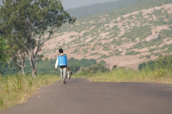 stock image An indian village man walking beside road carrying pestiside chemical on his back for spreading the chemical on his farm or yield to keep away the insects from crop