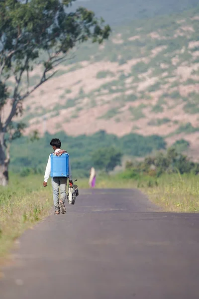 Kimyasal maddeleri tarlasına yaymak ya da haşereleri ekinlerden uzak tutmak için yol kenarında yürüyen bir Kızılderili köylüsü.