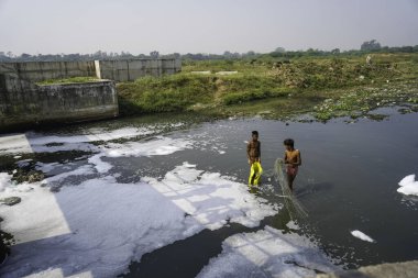 Aralık 2022, Raipur, Hindistan: Hint kanalizasyonunda balık ağıyla balık yakalayan iki çocuk, su kirliliği, kirlilik kontrolü, kirlilik konsepti