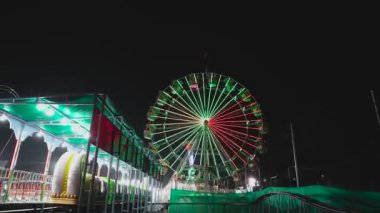 Renkli ışıklarla dönen dev dönme dolap manzarası, Hint karnavalı eğlence parkı geceleri