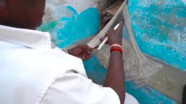 Balık tutmak için elleriyle ağ ören yaşlı bir adam, Hint köyünün yaşlı adamı balıkçı ağları örüyor.