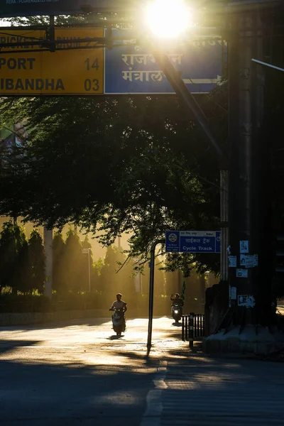 Morning yellow Sun rays striking on roads of raipur, chhattisgarh, Ghadi chowk road of raipur at morning, sun light touching the empty road at morning, Sunrays crossing through trees striking on road